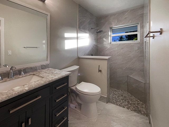 bathroom with tiled shower, vanity, and toilet