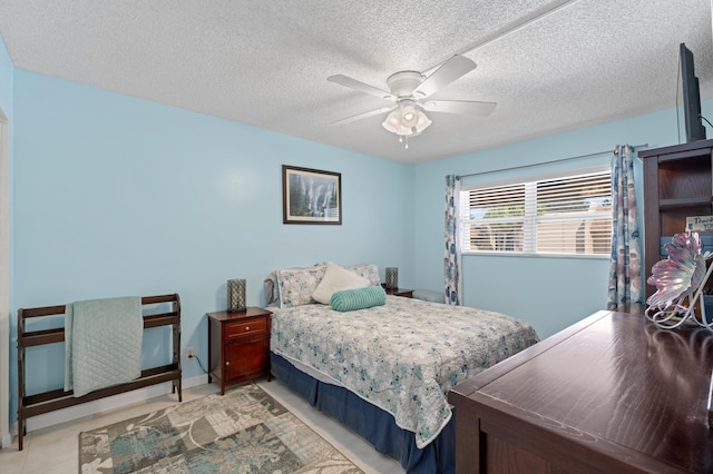 bedroom featuring ceiling fan, light tile patterned flooring, and a textured ceiling