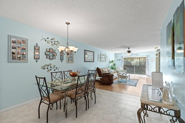 dining room featuring ceiling fan with notable chandelier, a textured ceiling, and light wood-type flooring