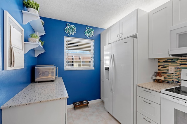 kitchen featuring a textured ceiling, white appliances, tasteful backsplash, and white cabinetry