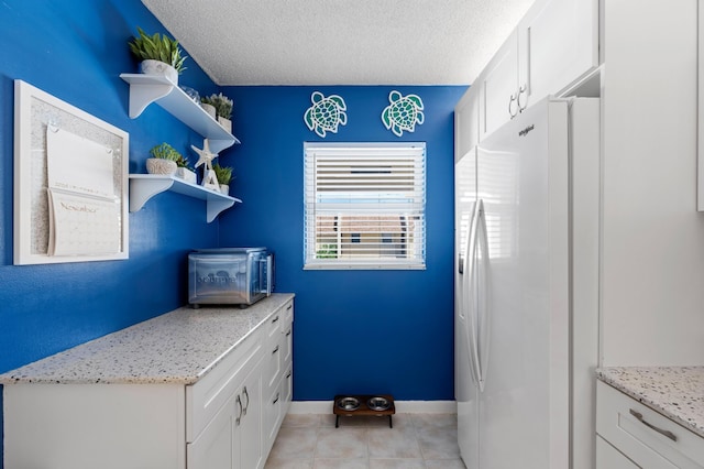 laundry area featuring light tile patterned floors and a textured ceiling