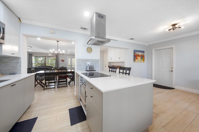 kitchen with pendant lighting, island range hood, appliances with stainless steel finishes, and tasteful backsplash