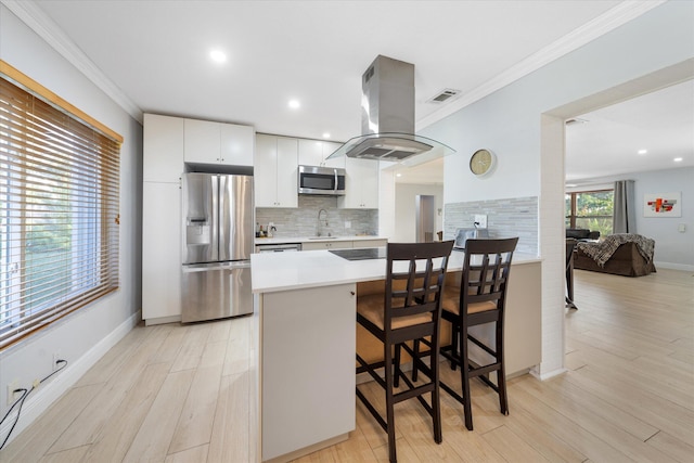 kitchen with island exhaust hood, stainless steel appliances, sink, light hardwood / wood-style flooring, and white cabinets