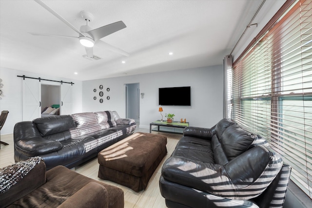 living room with a barn door, light hardwood / wood-style flooring, and ceiling fan