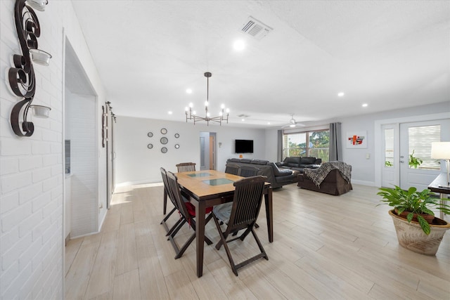 dining area featuring light hardwood / wood-style floors and ceiling fan with notable chandelier