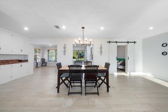 dining area with a chandelier and a barn door