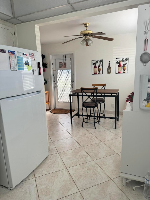 dining space with ceiling fan, a drop ceiling, and light tile patterned floors