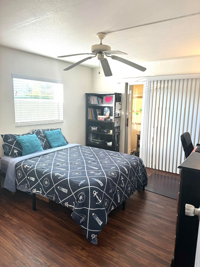 bedroom with a textured ceiling, ceiling fan, and dark wood-type flooring