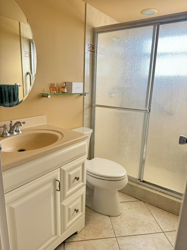 bathroom featuring tile patterned flooring, vanity, toilet, and a shower with shower door