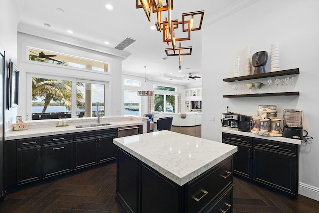 kitchen featuring ceiling fan, sink, a kitchen island, and a healthy amount of sunlight