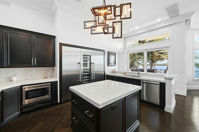 kitchen featuring built in appliances, a center island, hanging light fixtures, and sink