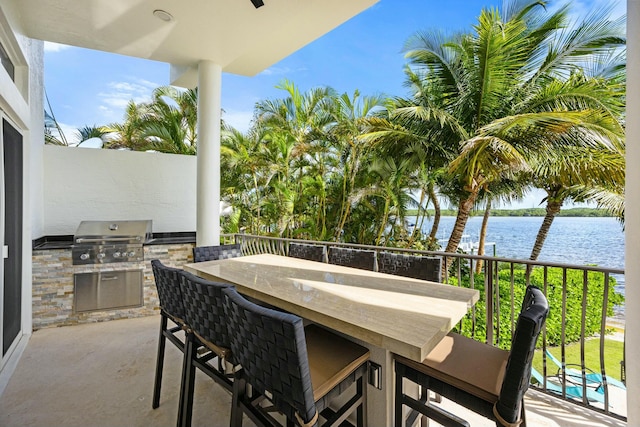 view of patio / terrace featuring an outdoor bar, a water view, area for grilling, and exterior kitchen