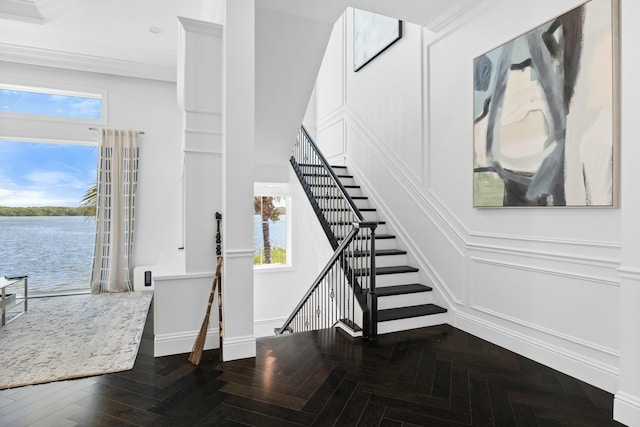 staircase with parquet flooring, a water view, a wealth of natural light, and crown molding