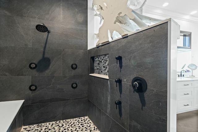 bathroom featuring a tile shower, vanity, and ornamental molding