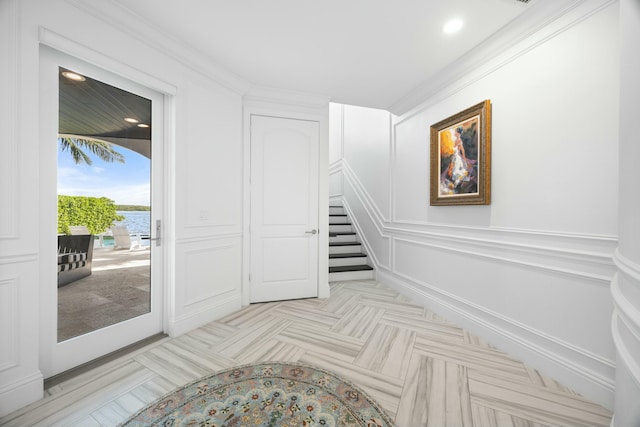 stairs with a water view and crown molding