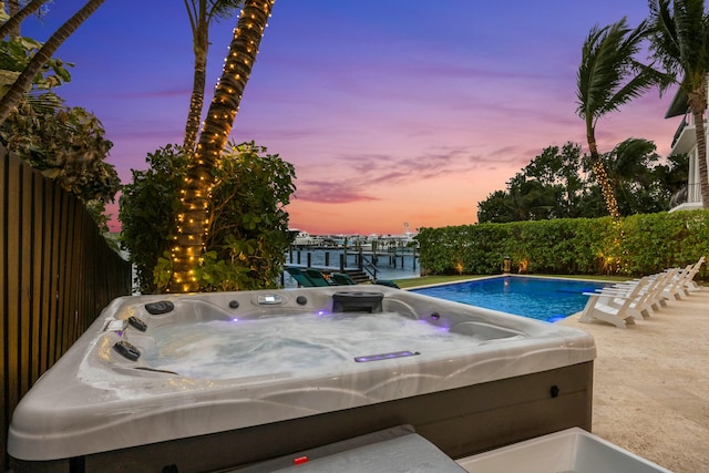 pool at dusk with a hot tub