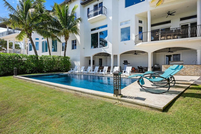 view of swimming pool with ceiling fan, a patio area, and a yard