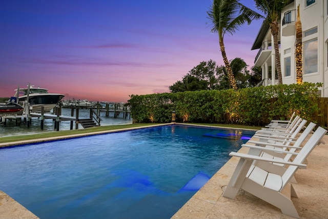 pool at dusk featuring a water view and a boat dock