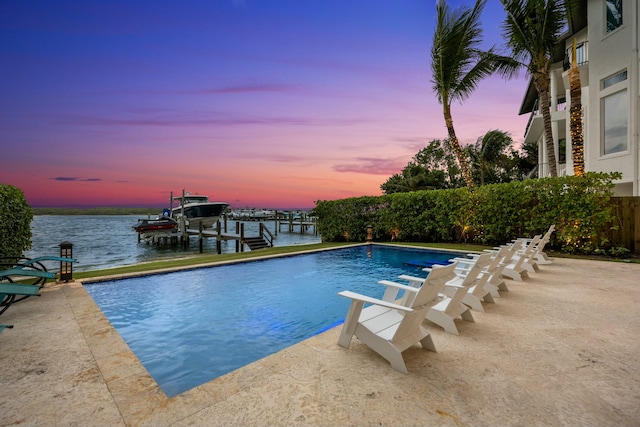 pool at dusk with a boat dock and a water view