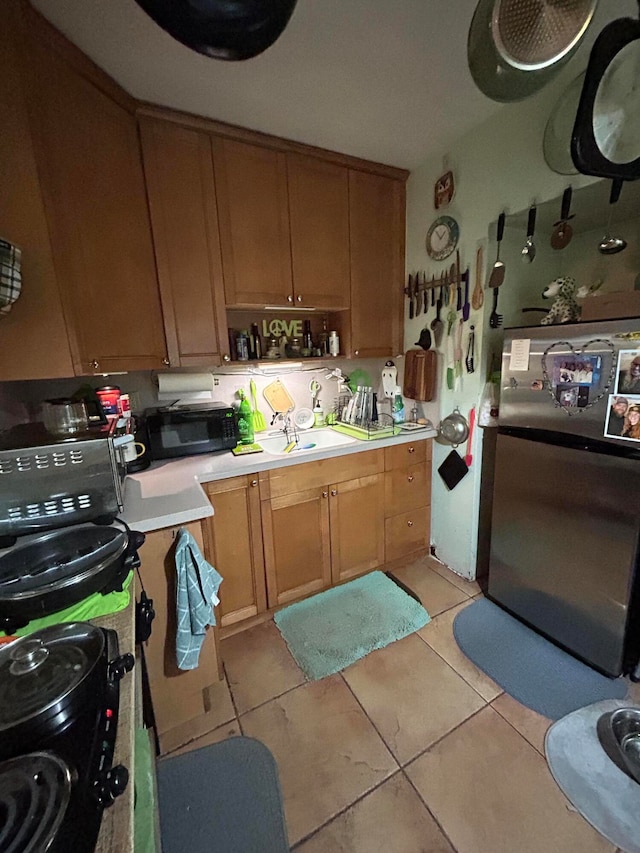 kitchen featuring sink, stainless steel refrigerator, and light tile patterned flooring