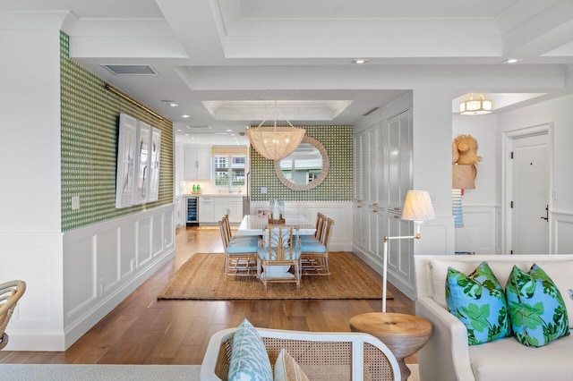 dining room with hardwood / wood-style flooring, a tray ceiling, beverage cooler, and a chandelier