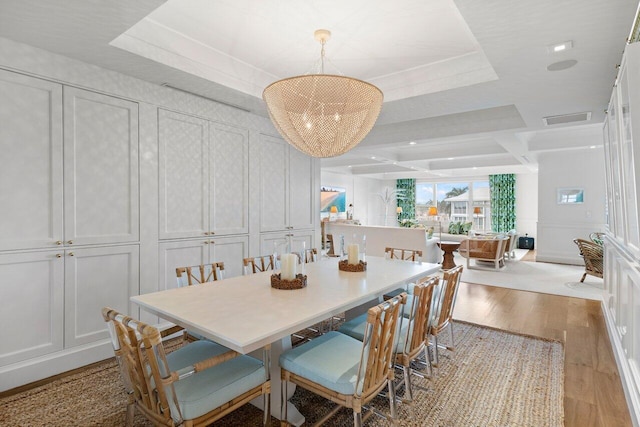 dining space featuring a raised ceiling and light wood-type flooring