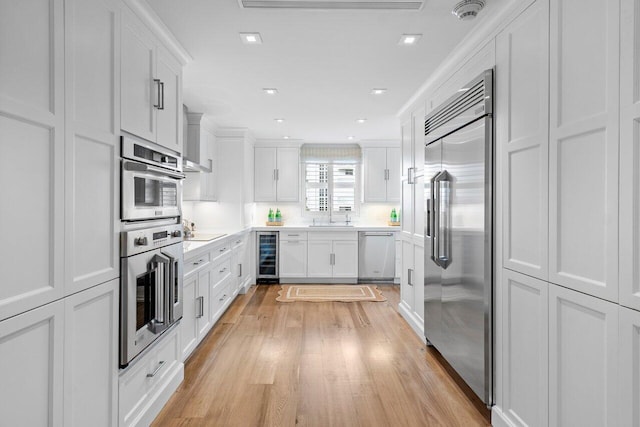 kitchen with white cabinets, appliances with stainless steel finishes, light hardwood / wood-style flooring, and wine cooler