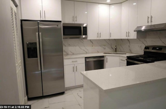 kitchen with tasteful backsplash, sink, white cabinets, and appliances with stainless steel finishes