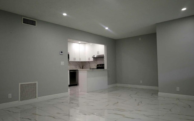 interior space featuring white cabinets, kitchen peninsula, appliances with stainless steel finishes, and tasteful backsplash