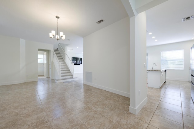 empty room with light tile patterned floors, sink, and a chandelier