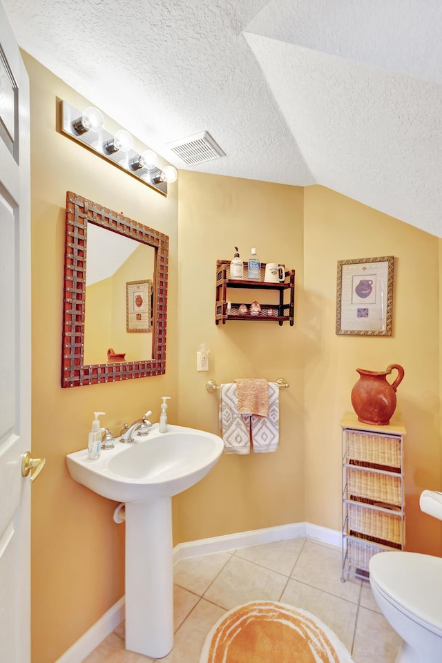 bathroom featuring tile patterned floors, a textured ceiling, lofted ceiling, and toilet