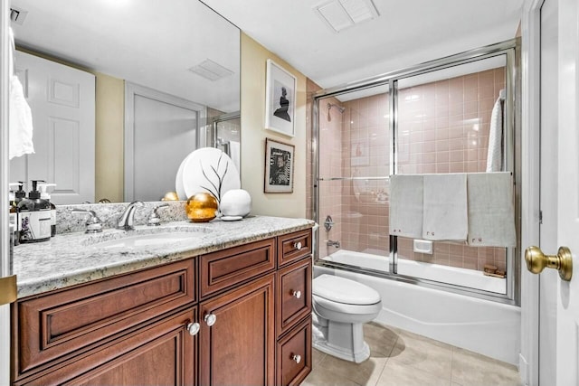 full bathroom featuring shower / bath combination with glass door, tile patterned flooring, vanity, and toilet