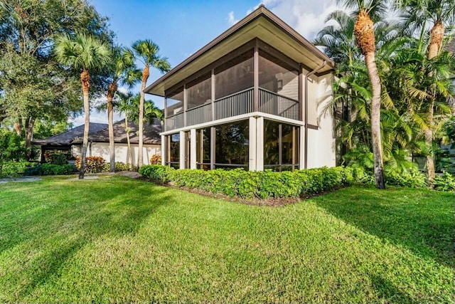 rear view of house featuring a sunroom and a yard