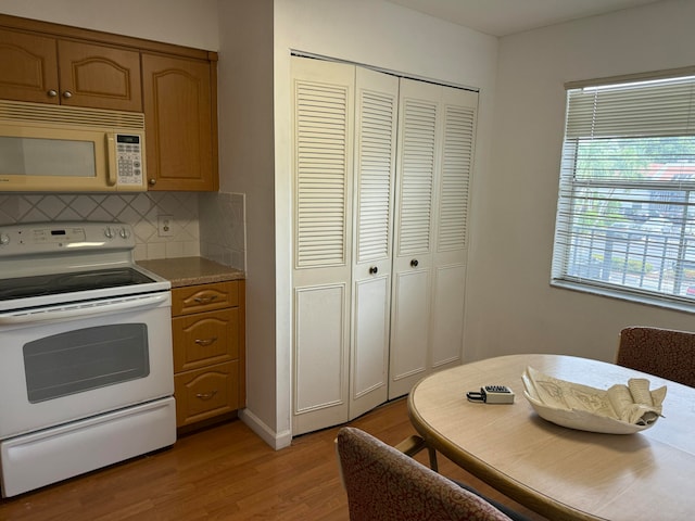 kitchen with electric range, decorative backsplash, and light hardwood / wood-style flooring