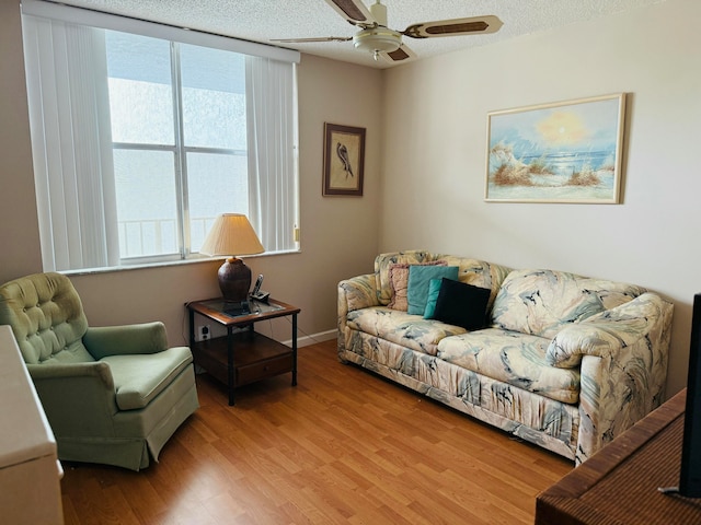 living room featuring ceiling fan, wood-type flooring, and a textured ceiling