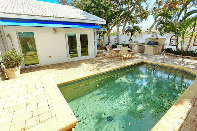 view of swimming pool featuring french doors, a patio, and an outdoor kitchen