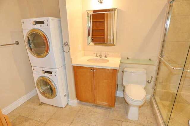 bathroom featuring vanity, toilet, a shower with shower door, and stacked washer / drying machine