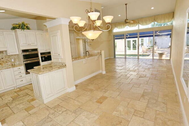 kitchen featuring backsplash, white cabinets, double oven, decorative light fixtures, and light stone counters