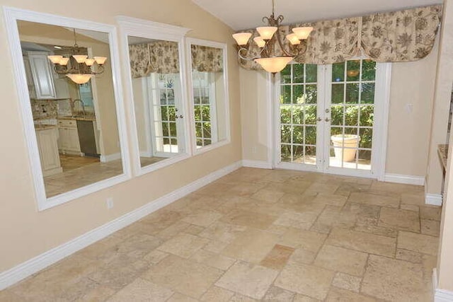 unfurnished dining area featuring a notable chandelier, lofted ceiling, sink, and french doors