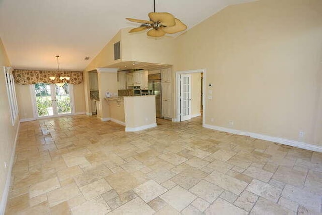 unfurnished living room with ceiling fan with notable chandelier and high vaulted ceiling