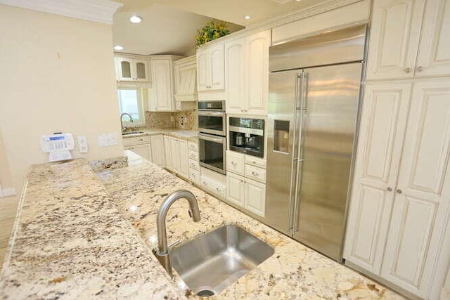 kitchen featuring light stone countertops, appliances with stainless steel finishes, backsplash, and sink