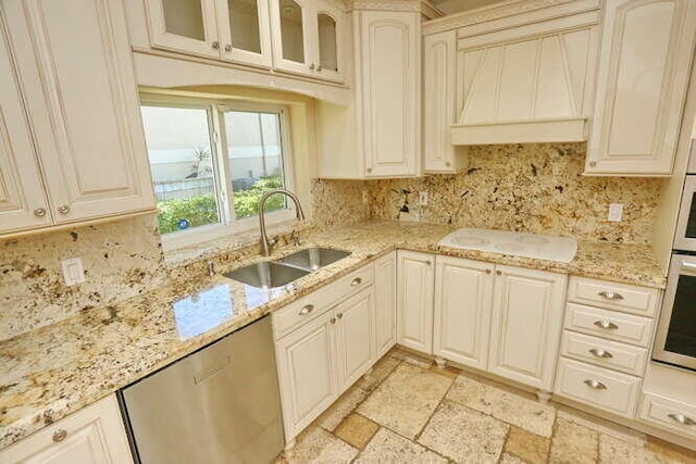 kitchen with appliances with stainless steel finishes, light stone counters, custom exhaust hood, sink, and cream cabinetry