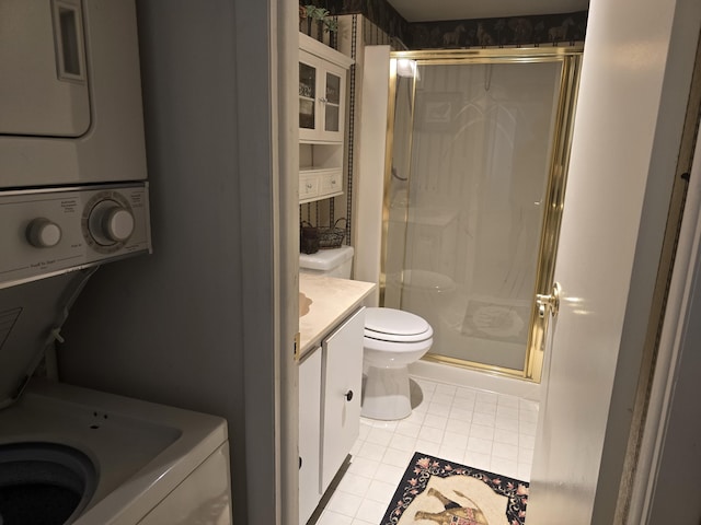 bathroom featuring tile patterned floors, toilet, vanity, a shower with shower door, and stacked washer and clothes dryer