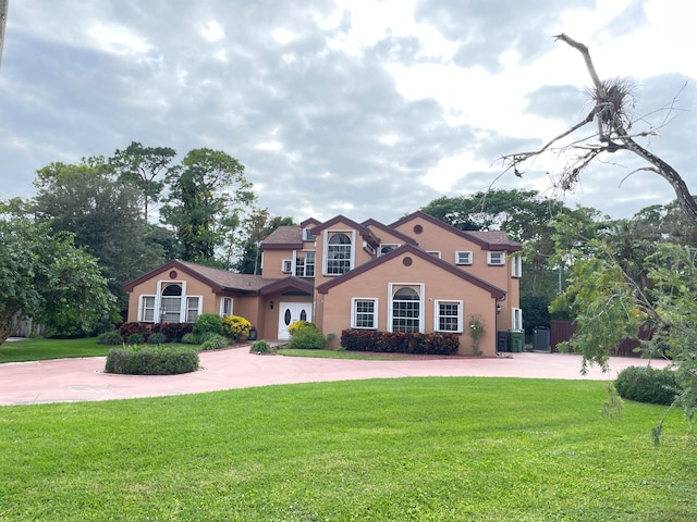 mediterranean / spanish house featuring central air condition unit and a front lawn