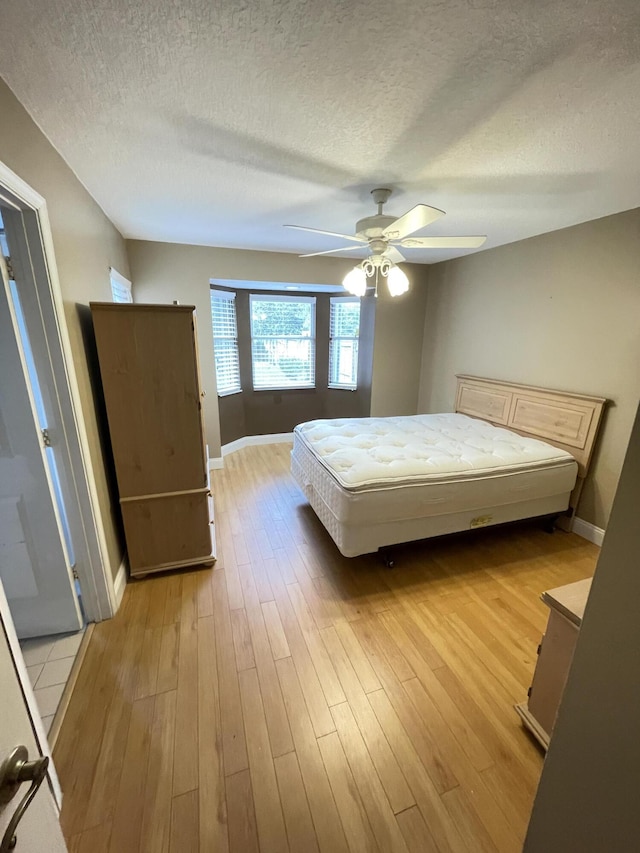 unfurnished bedroom with a textured ceiling, light hardwood / wood-style flooring, and ceiling fan