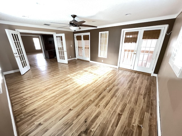 unfurnished living room with hardwood / wood-style floors, ceiling fan, ornamental molding, and french doors