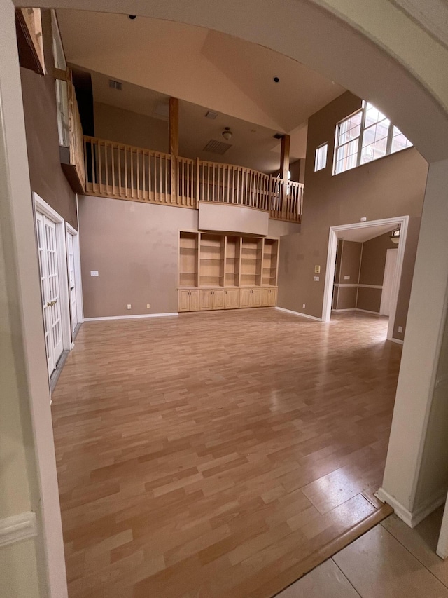 unfurnished living room featuring light hardwood / wood-style floors and high vaulted ceiling