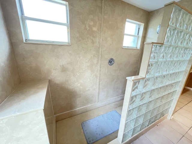 bathroom with tile patterned flooring, plenty of natural light, and walk in shower