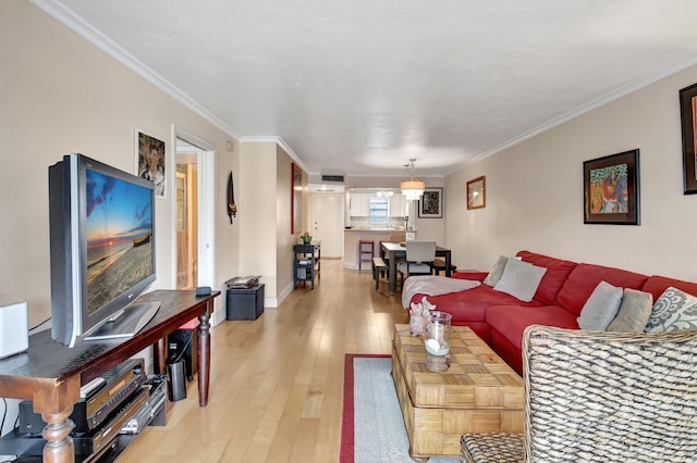 living room with ornamental molding, light wood-type flooring, and baseboards