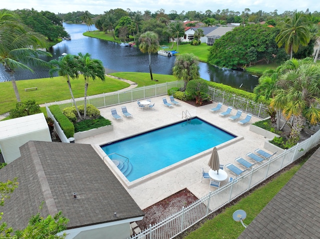 view of swimming pool with a patio area, a lawn, and a water view